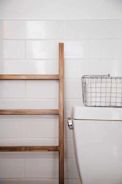 Bathroom with a cute ladder and collapsible storage bin upon toilet tank.