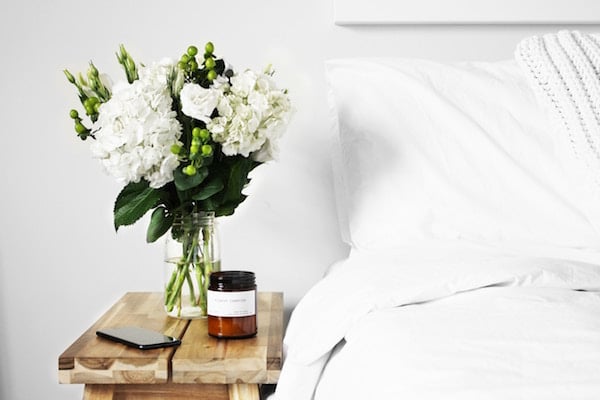 Flower and phone upon nightstand in bright bedroom